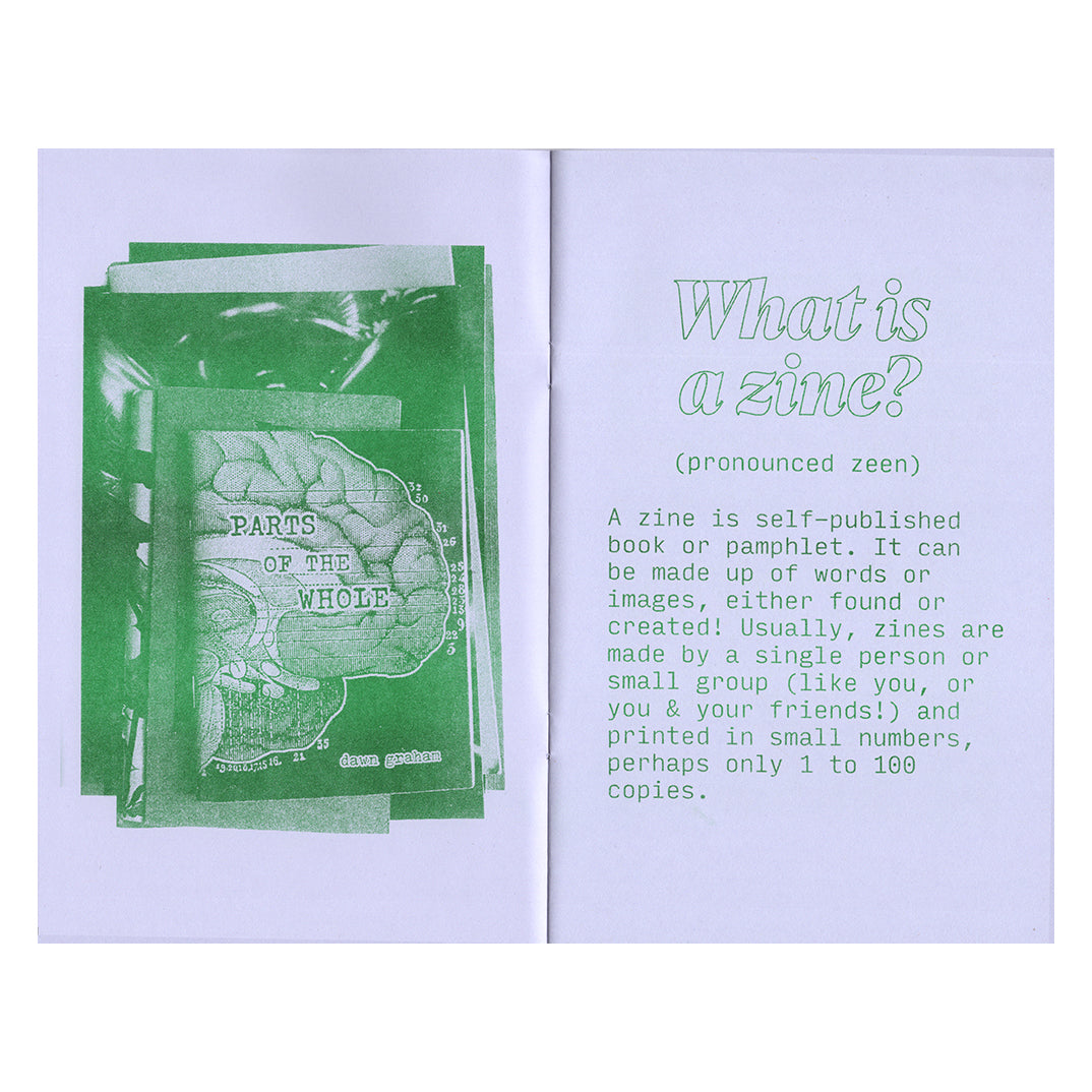 An open spread of the book, Risograph printed in green on light purple paper. On the left page is a photo of a stack of zines, and on the right page a short paragraph explains “What is a Zine?”